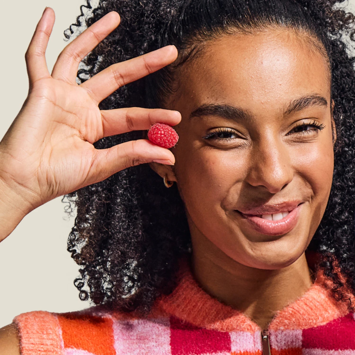 Smiling teen girl holding WUKA Teen Iron Support Gummies in raspberry flavour – vegan vitamin supplement to boost energy and reduce fatigue.